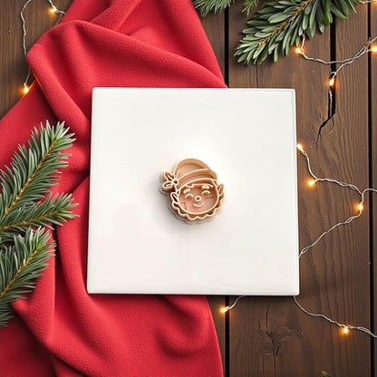 Elf face polymer clay cutter on red background with festive greenery