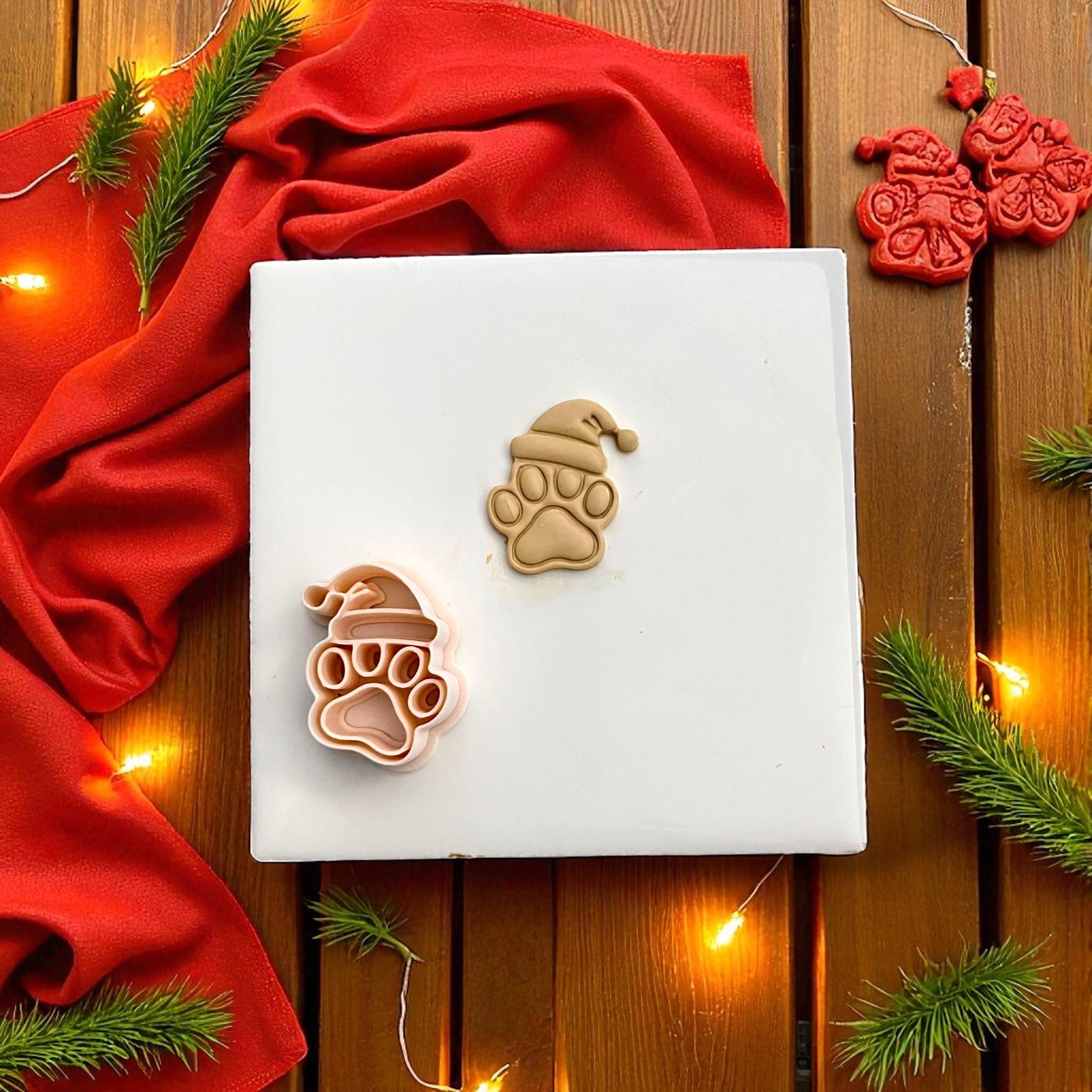Christmas paw print polymer clay imprint with Santa hat on tan clay with festive lights