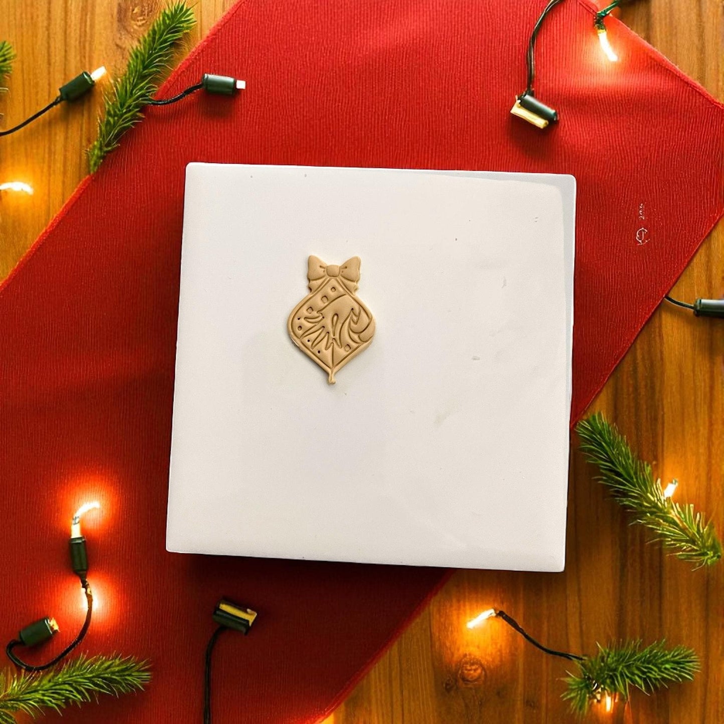 Christmas ornament clay design featuring Grinch hand and bow on red background