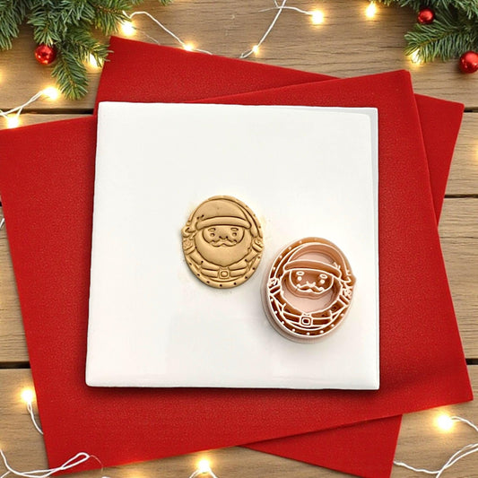 Santa cutter and clay imprint side by side on white tile with red cloth