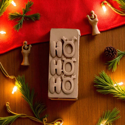 Close-up of Ho Ho Ho clay design with reindeer ears and pine decor
