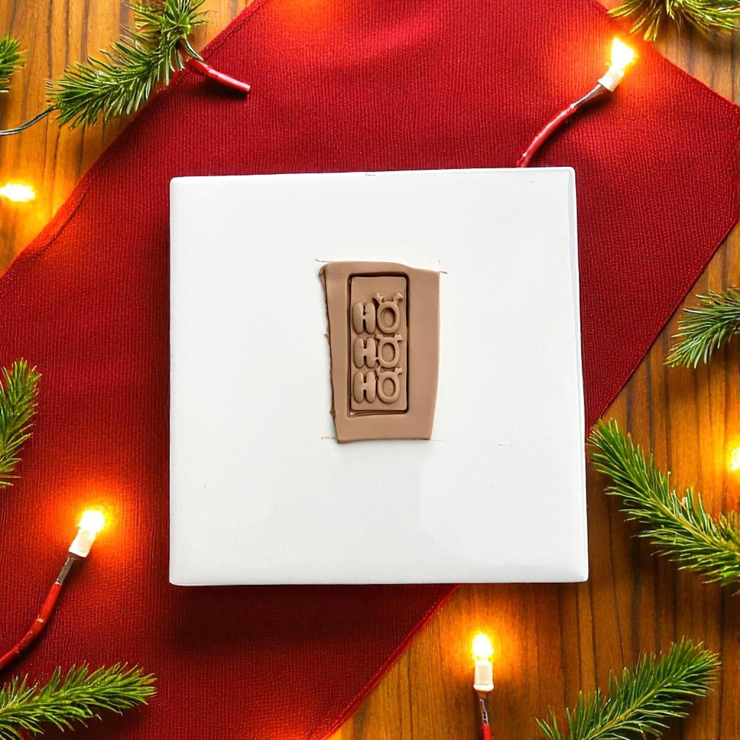 Ho Ho Ho polymer clay imprint on red background with Christmas lights