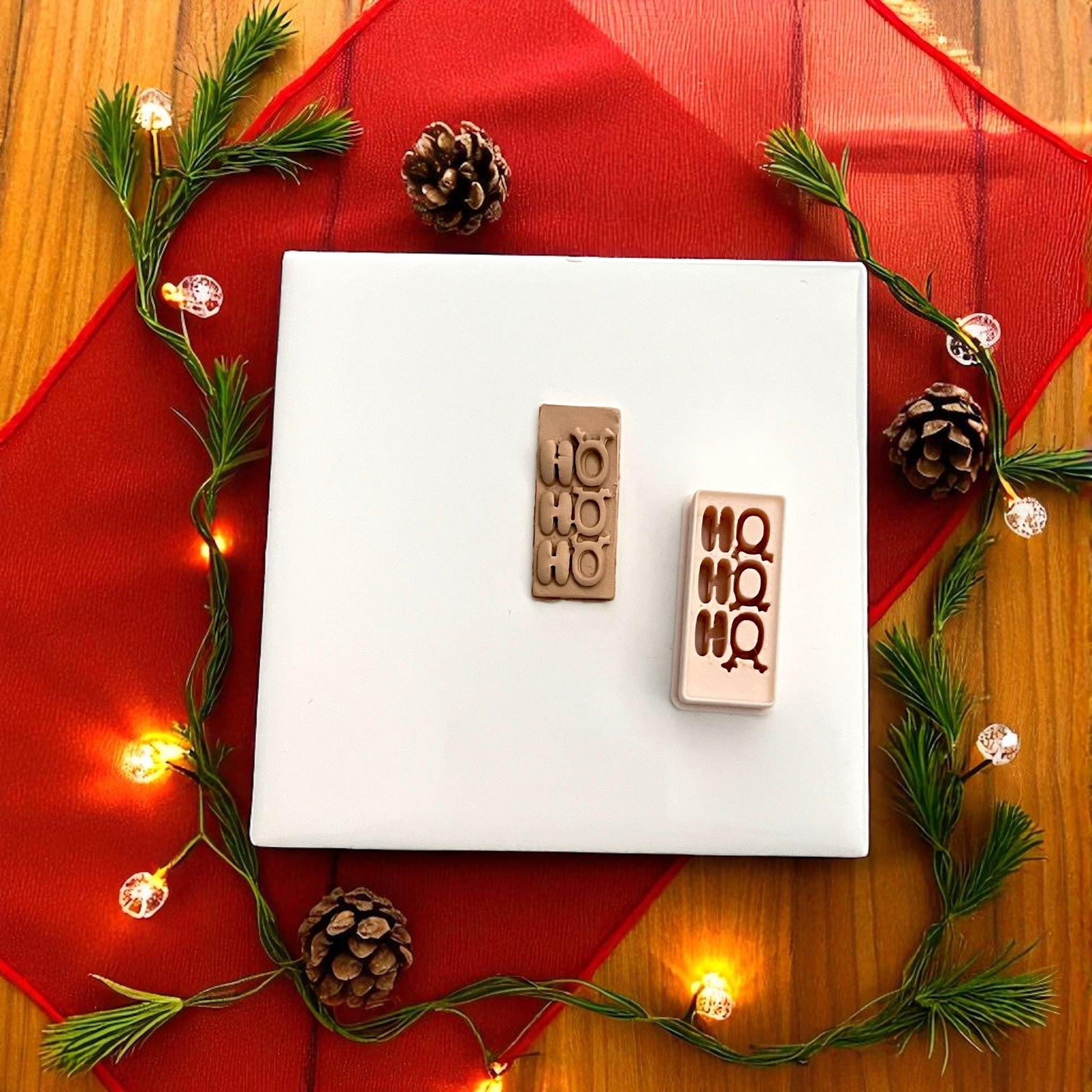 Polymer clay cutter and Ho Ho Ho imprint side by side with holiday lights