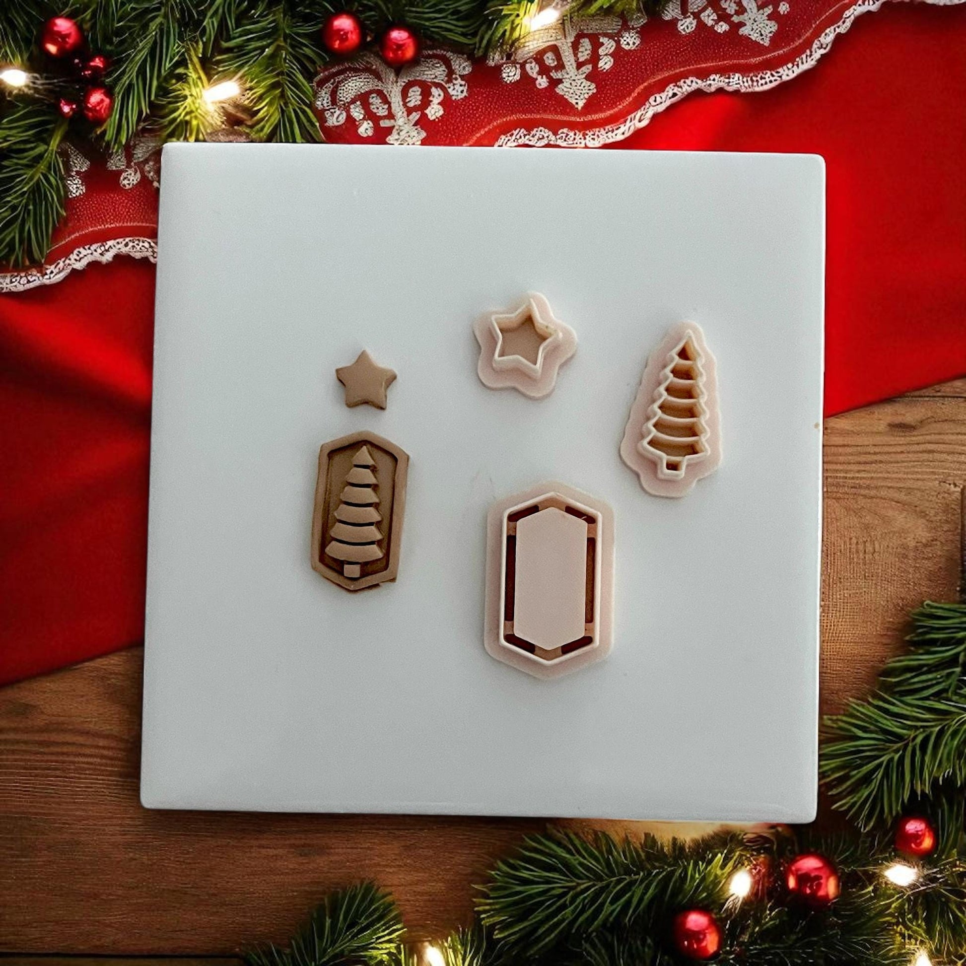 Polymer clay cutters and matching impressions shaped like star, tree, and frame on white tile