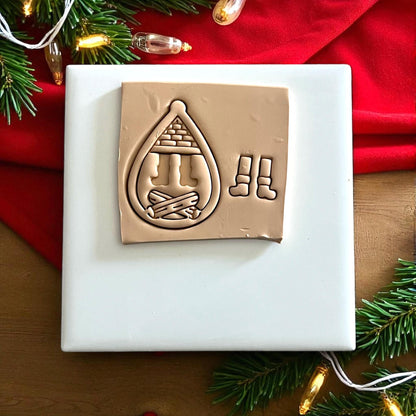 Santa boots polymer clay cutter and imprint on white tile with red cloth and Christmas greenery