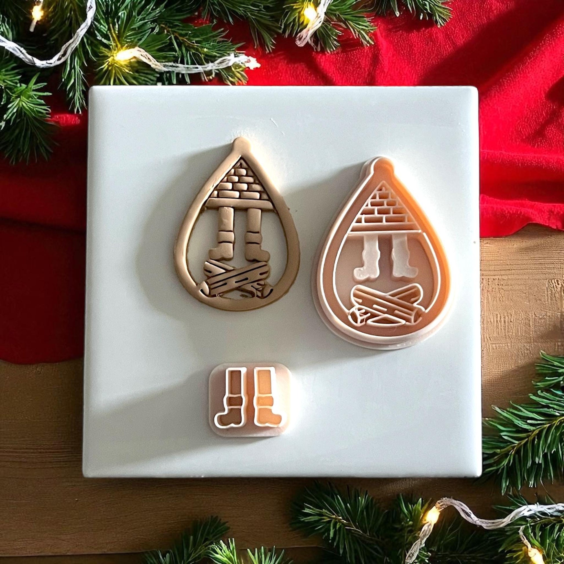 Polymer clay chimney cutter and Santa boots imprint side by side on white tile