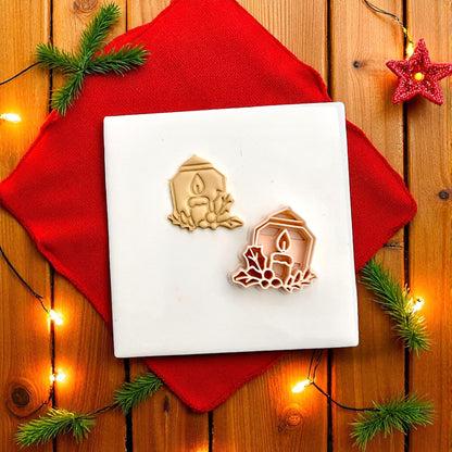 Holiday candle clay imprint centered on white tile with red background and Christmas lights