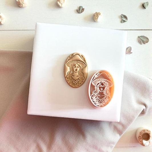 Mushroom lady cutter and clay impression shown together on white tile