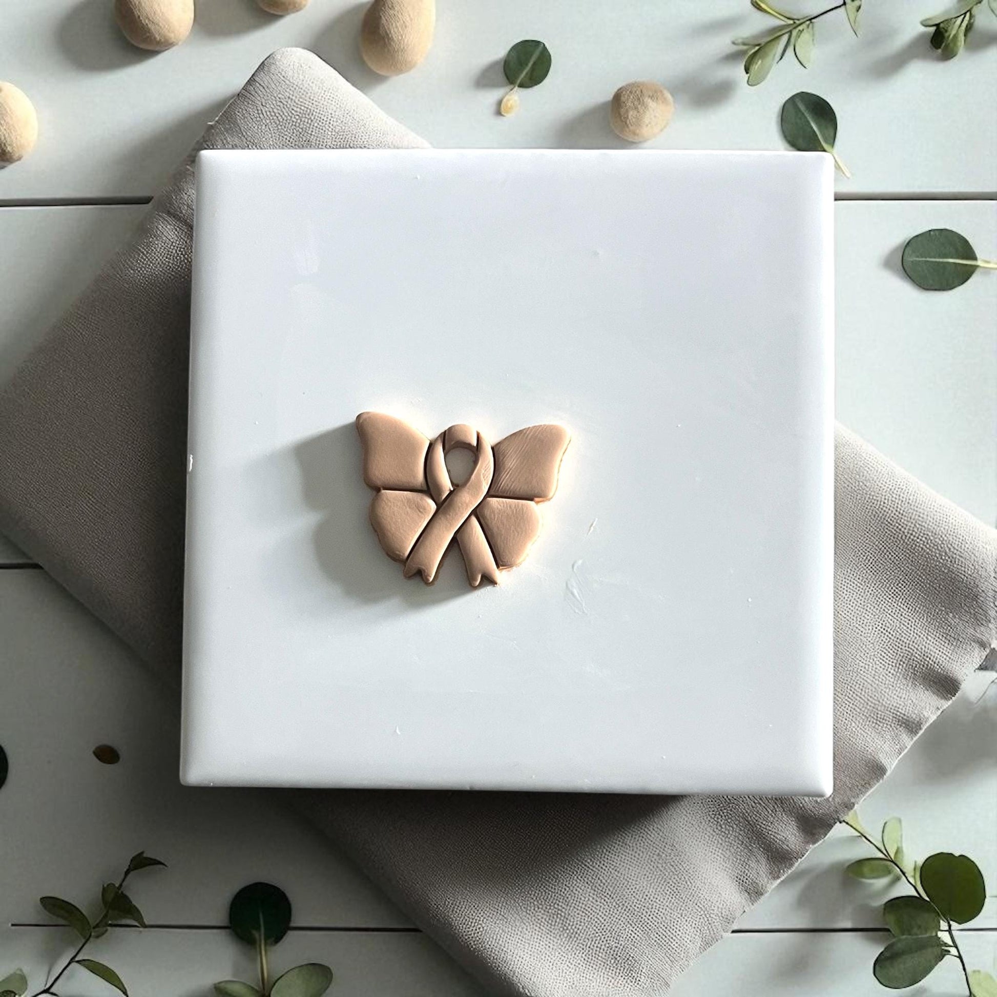 Butterfly ribbon clay cutter close-up on fabric with soft sunlight and petals