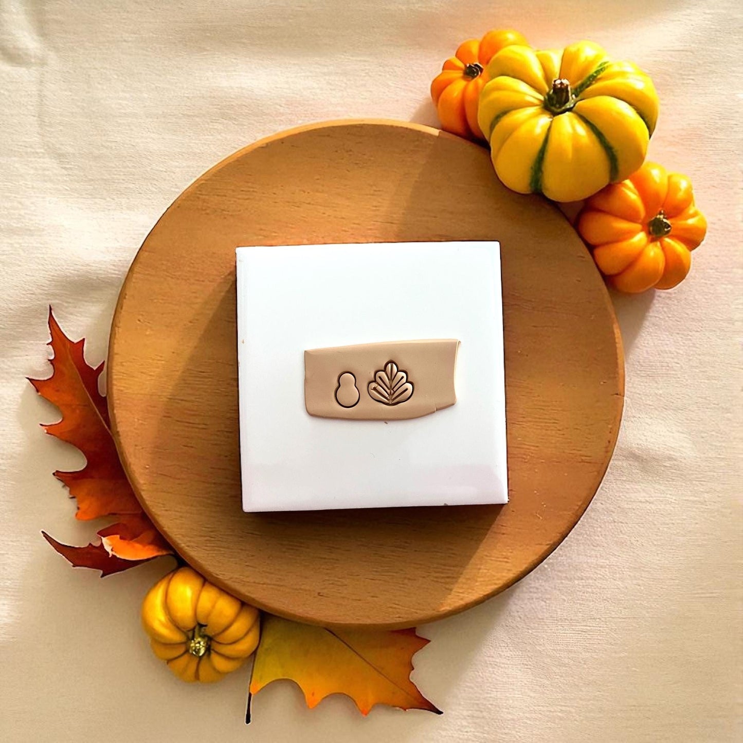 Polymer clay turkey design on wooden plate with pumpkin and autumn leaves