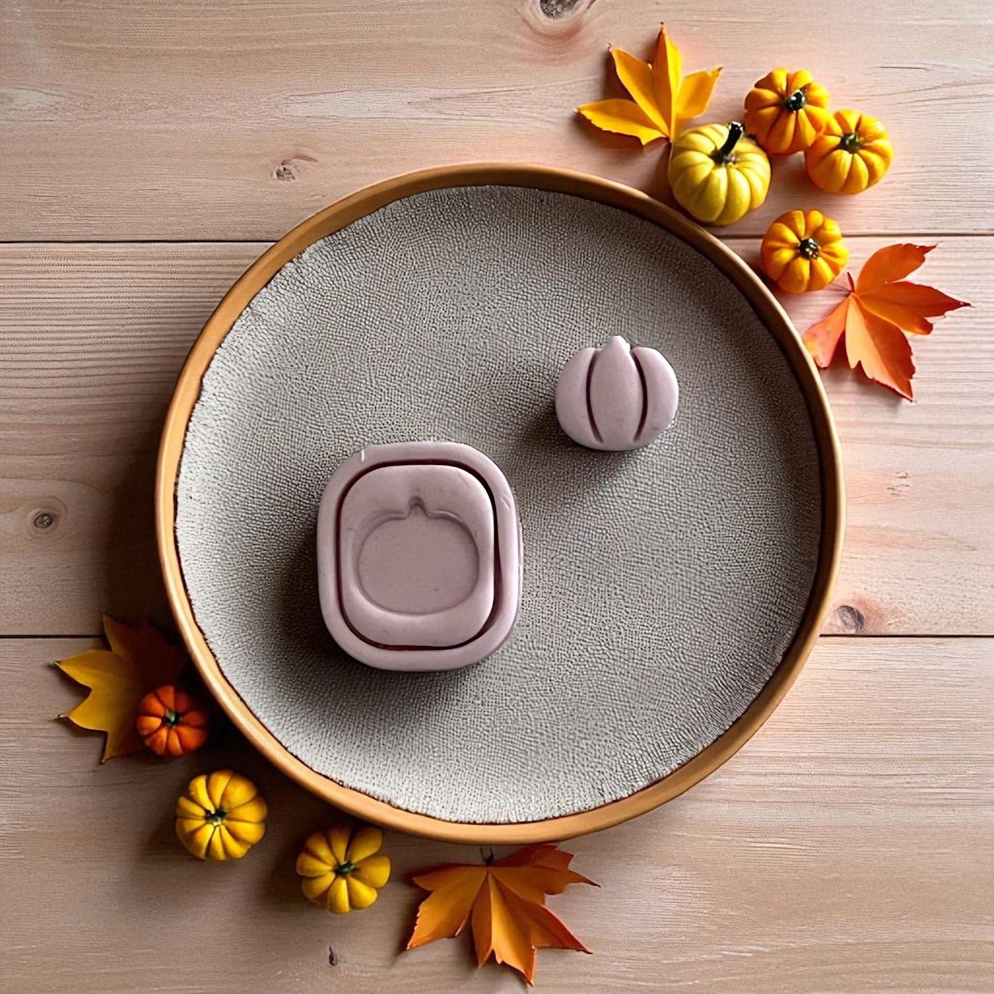 Pumpkin frame and stud clay cutters displayed on white tile with pumpkins and leaves