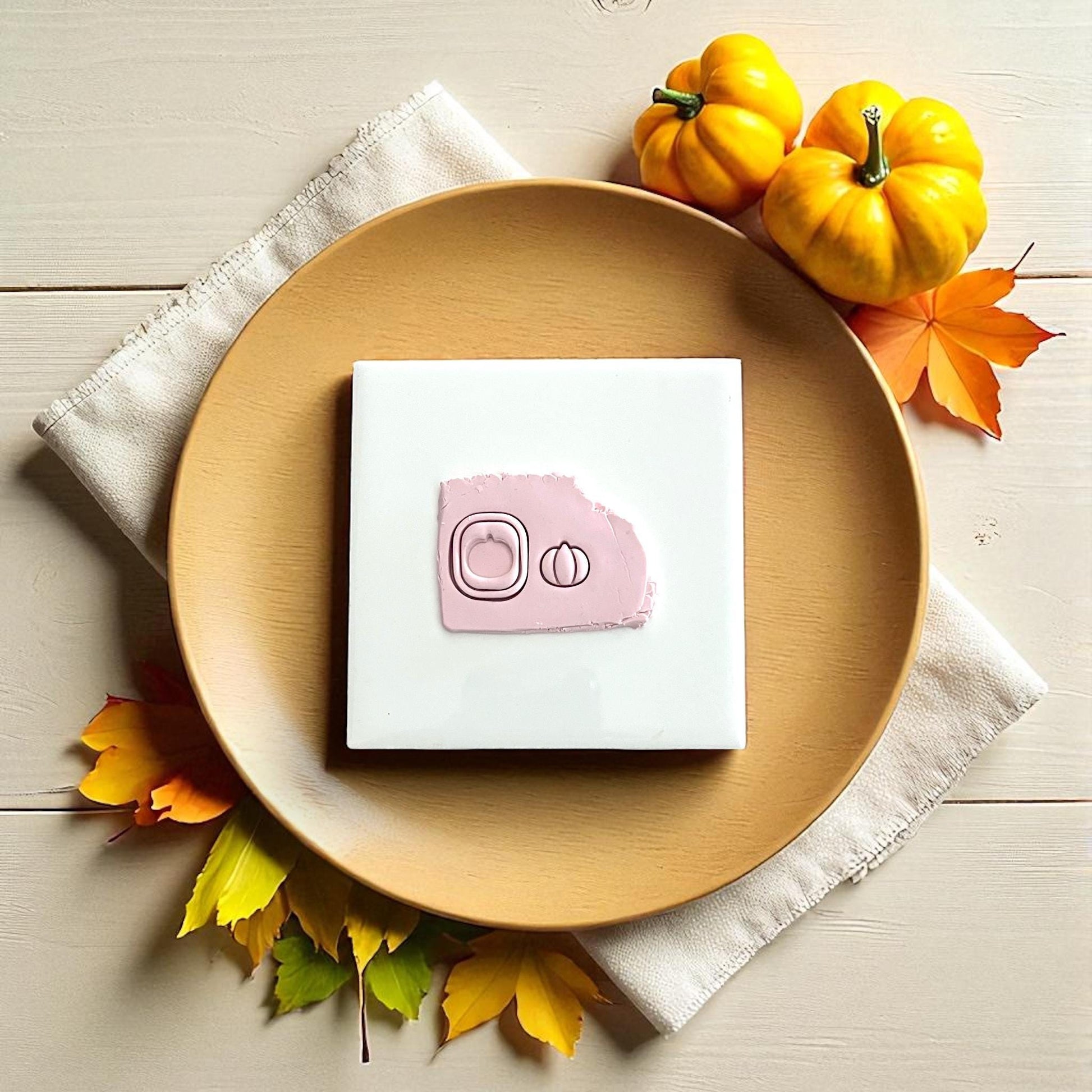 Pumpkin clay impression on white tile surrounded by fall decor