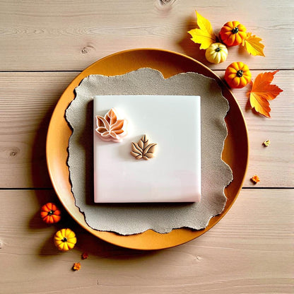 Polymer clay leaf cutter displayed on white tile with pumpkins and beige cloth
