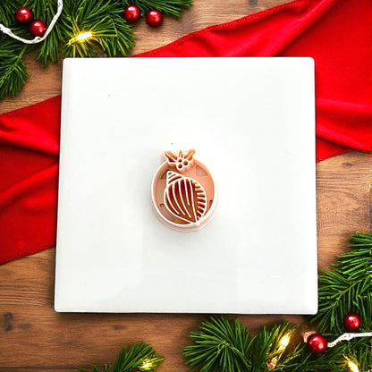 Shell clay cutter shown on white tile with Christmas greenery and red decorations