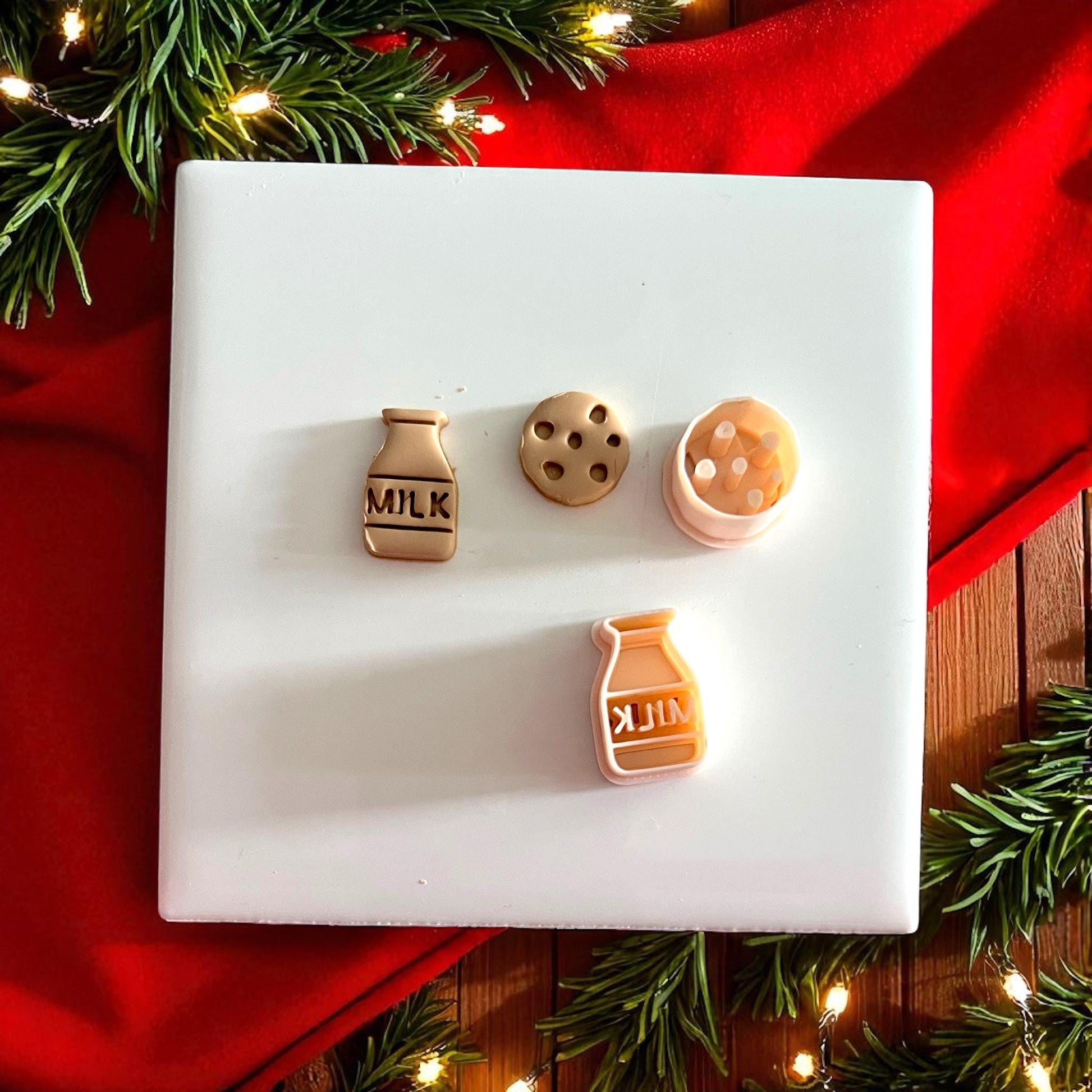 Milk and cookie polymer clay pieces displayed on white tile with festive decor