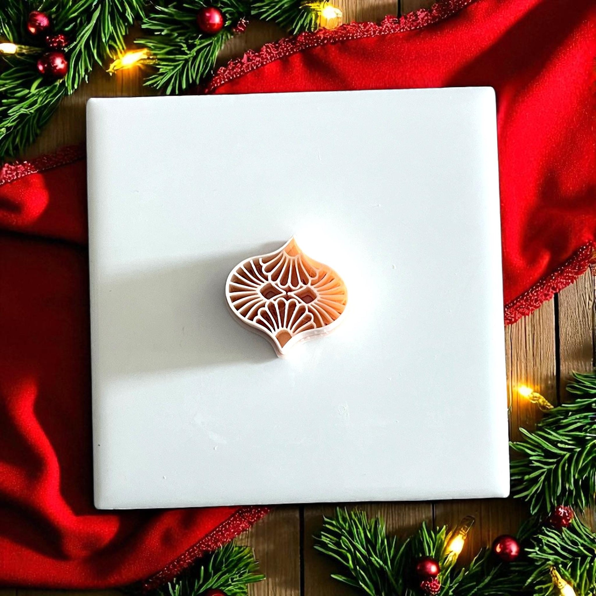 small ornament clay cutter displayed on white board with red ribbon and greenery