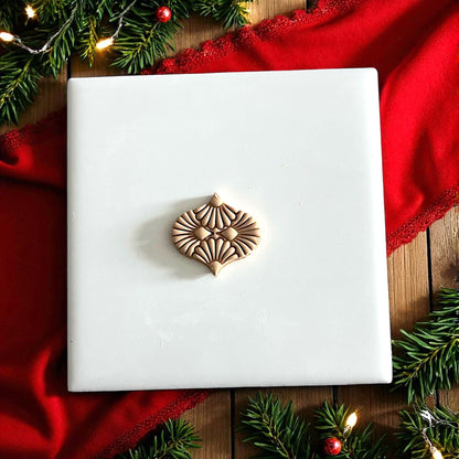 closeup polymer clay ornament impression with greenery and red fabric