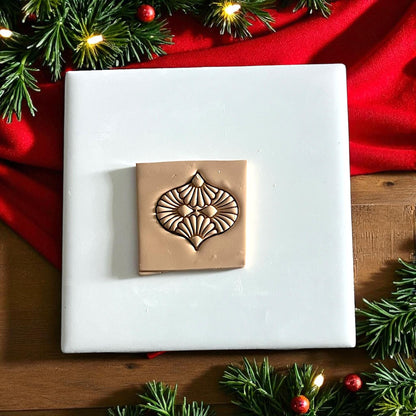 clay sheet with detailed ornament cutter imprint surrounded by Christmas lights