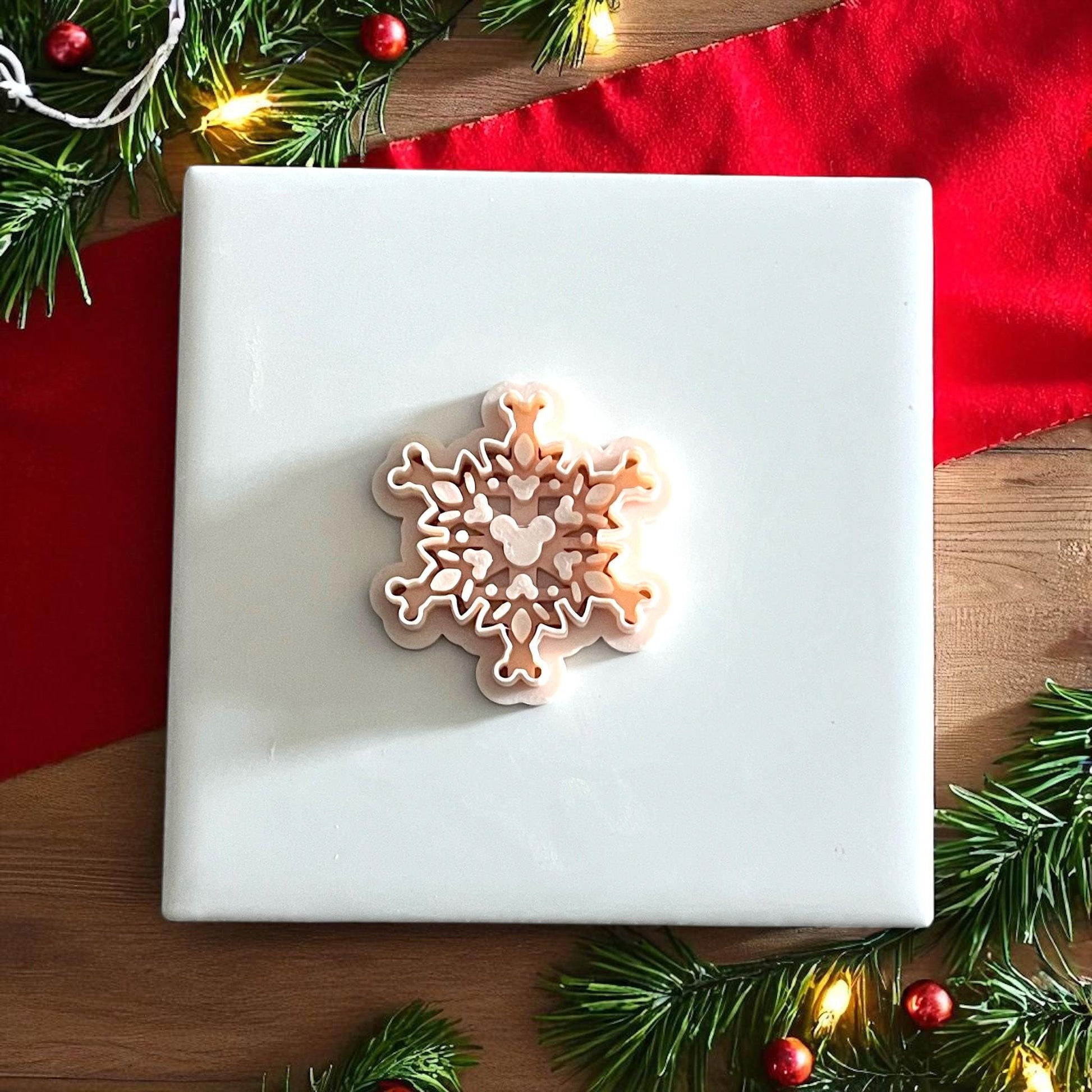mouse snowflake clay cutter displayed on white tile with red cloth and greenery