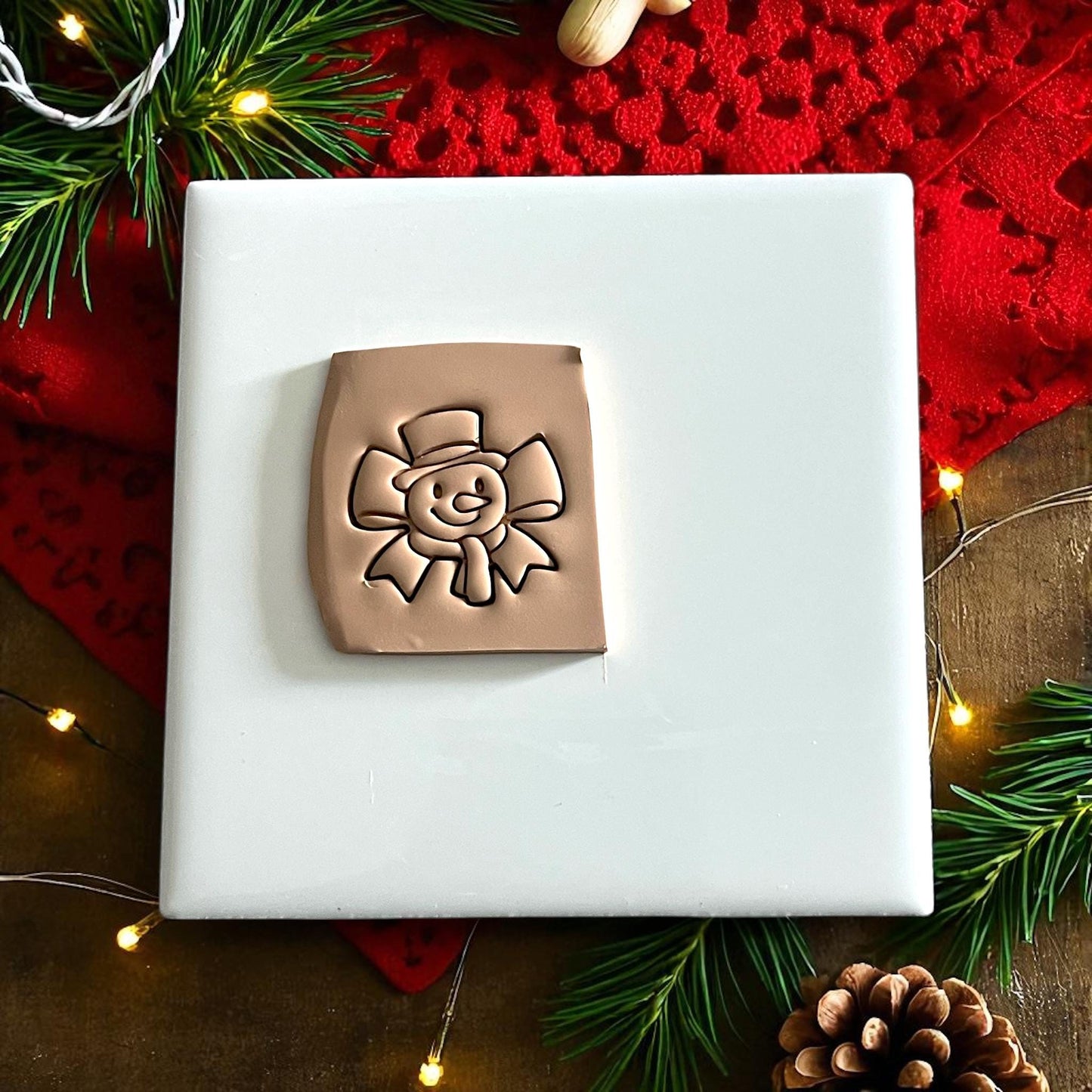 Square clay slab featuring snowman ribbon bow impression for polymer clay projects