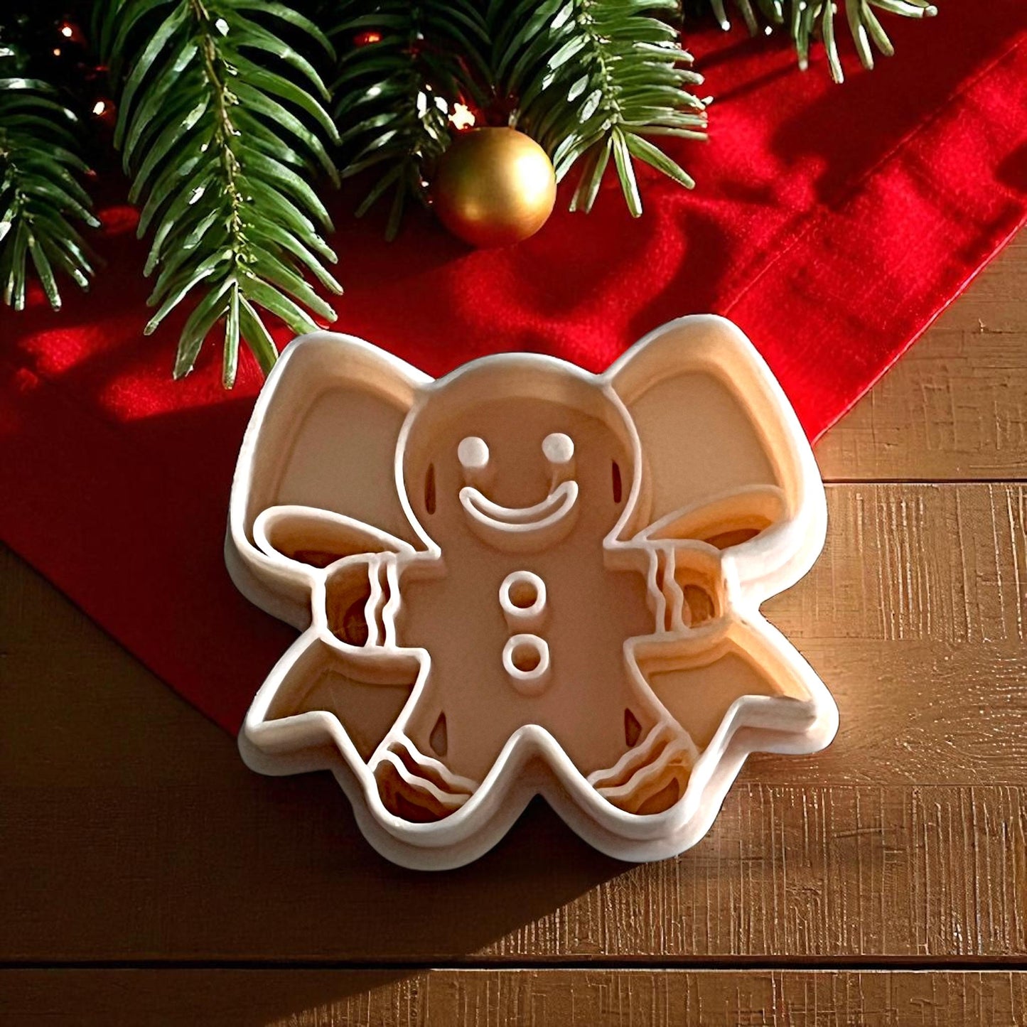 Gingerbread bow polymer clay cutter on white tile with red cloth and holiday greenery