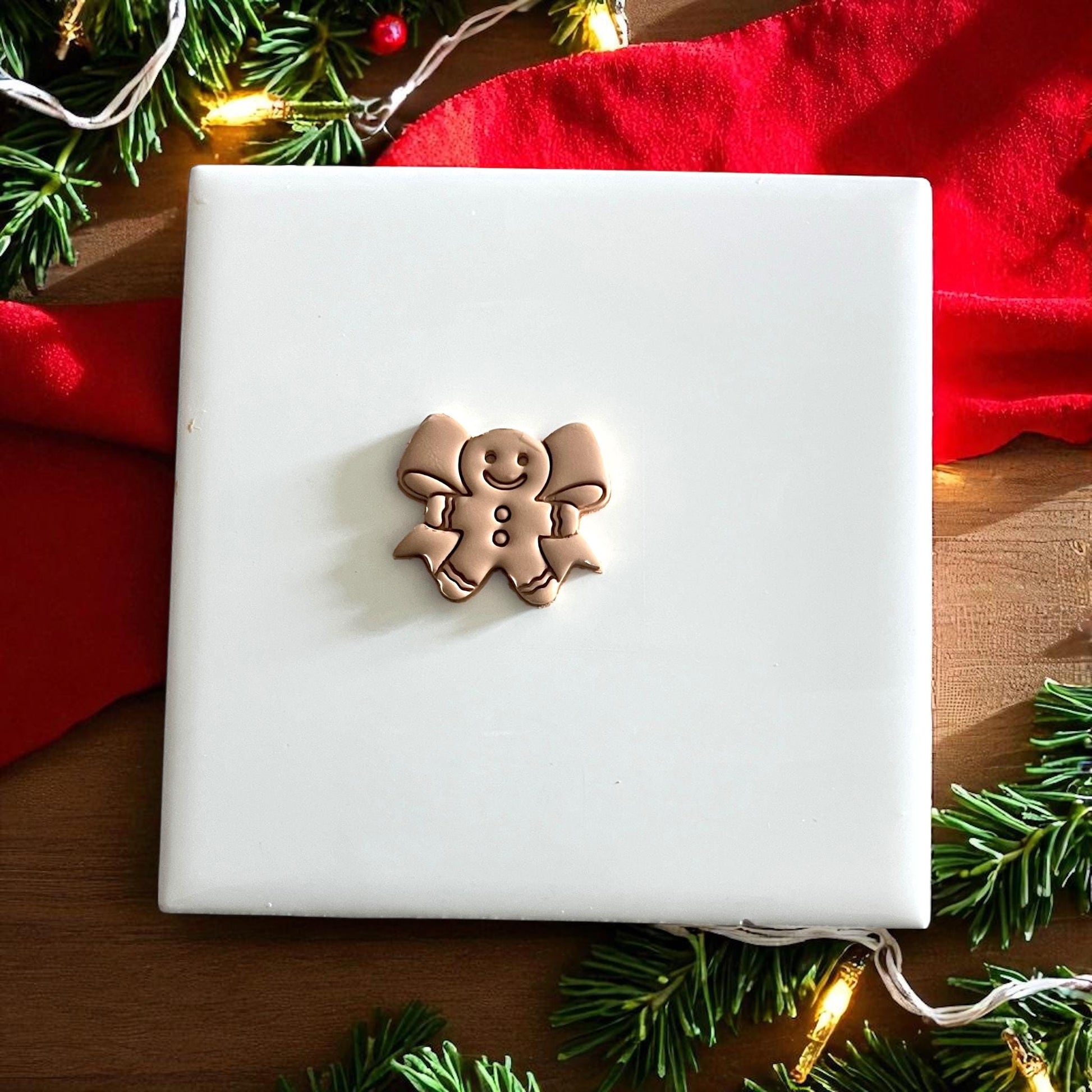 Clay impressions and cutter of gingerbread man with bow displayed on festive backdrop