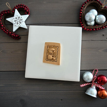 Tan snowman postage stamp clay imprint on wood background with Christmas ornaments