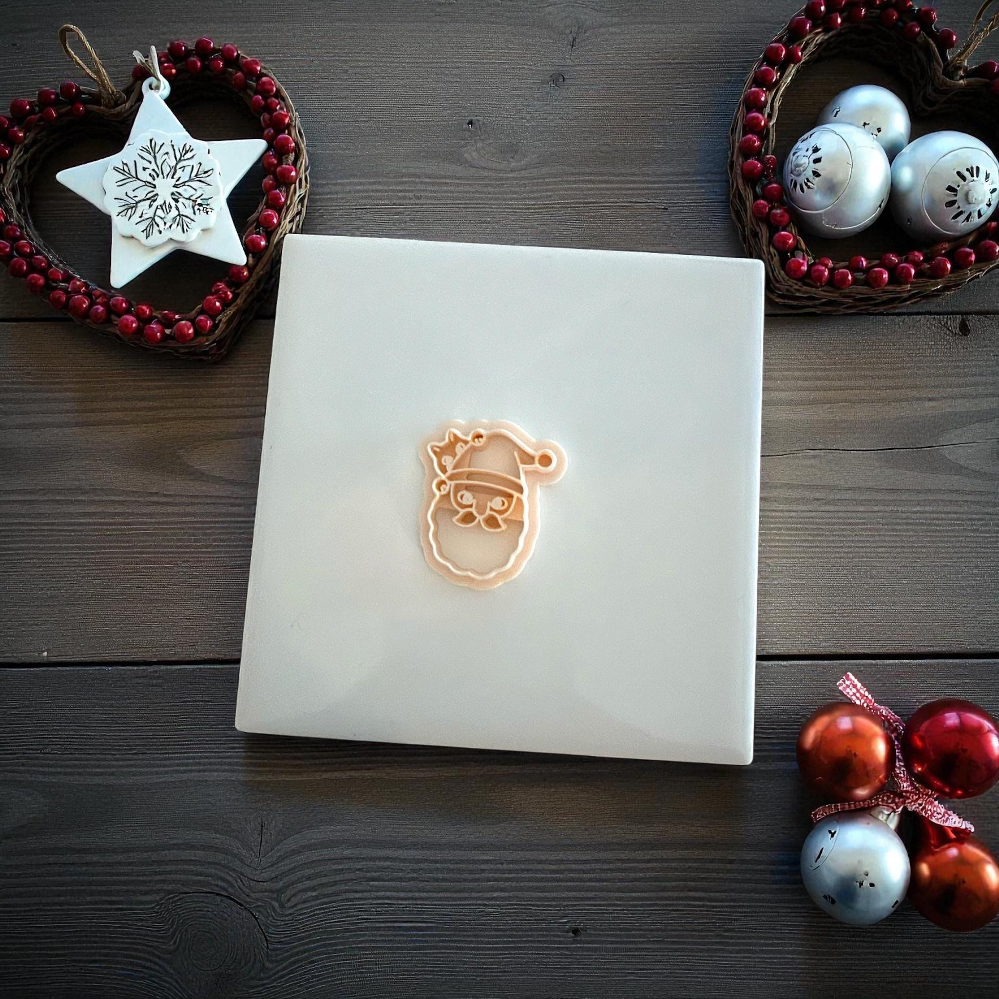 Santa cat polymer clay imprint and cutter displayed on white tile with Christmas ornaments