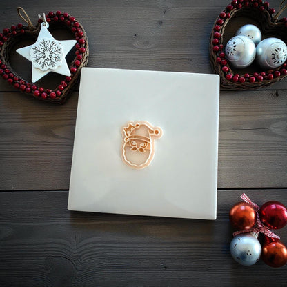 Santa cat polymer clay imprint and cutter displayed on white tile with Christmas ornaments