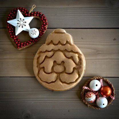 Santa ornament clay imprint on wood background surrounded by red and silver ornaments