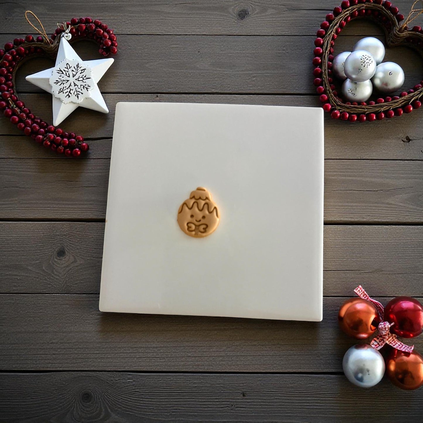 Gingerbread ornament clay imprint centered on white tile with Christmas ornaments