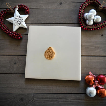 Gingerbread ornament clay imprint centered on white tile with Christmas ornaments