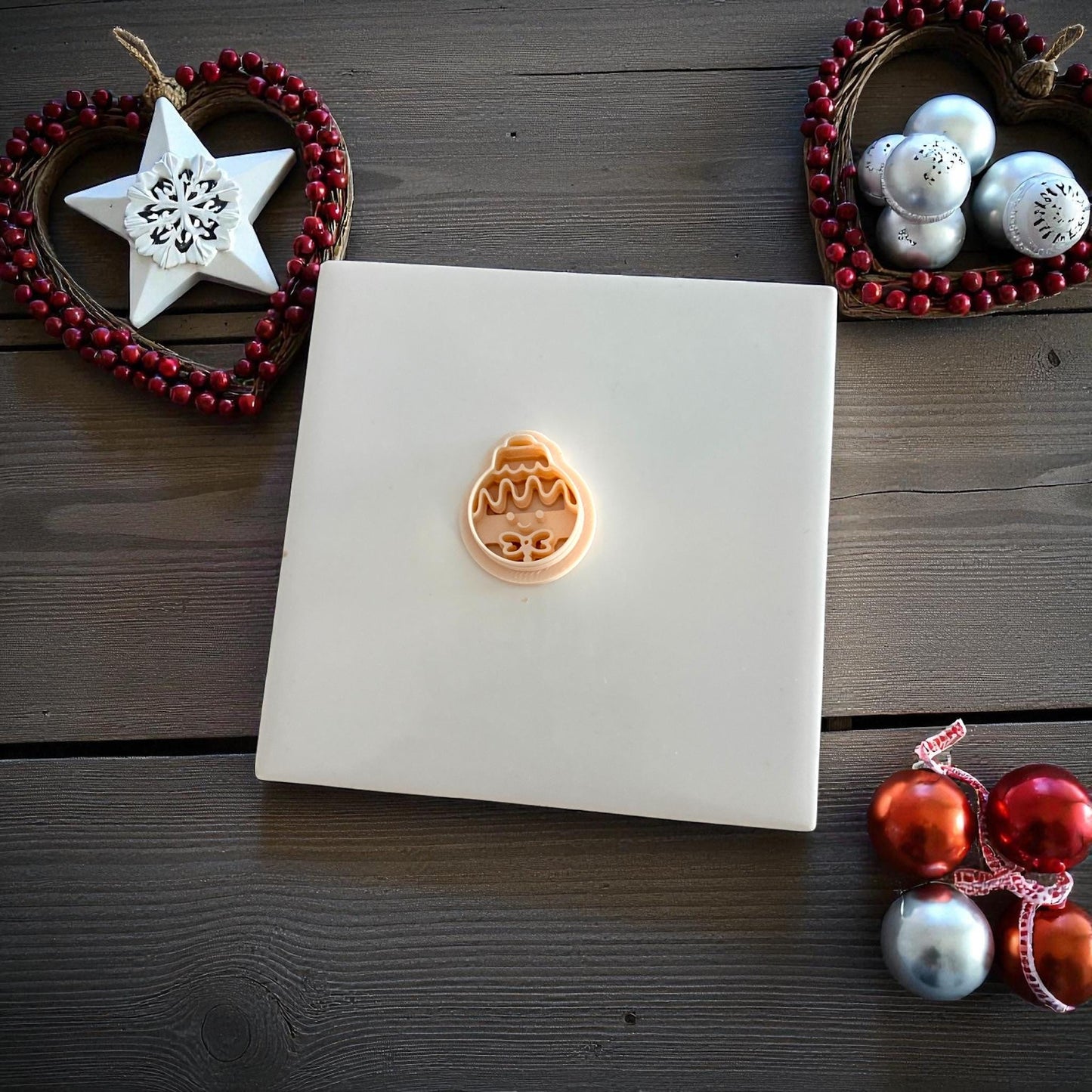 Small gingerbread ornament clay imprint centered on white tile with ornaments