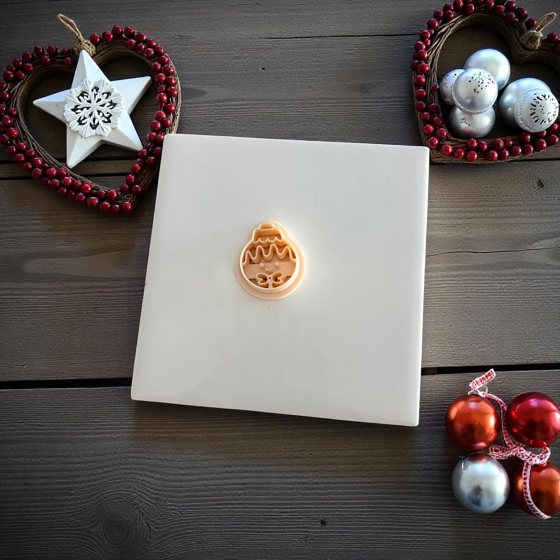Small gingerbread ornament clay imprint centered on white tile with ornaments