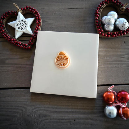 Small gingerbread ornament clay imprint centered on white tile with ornaments
