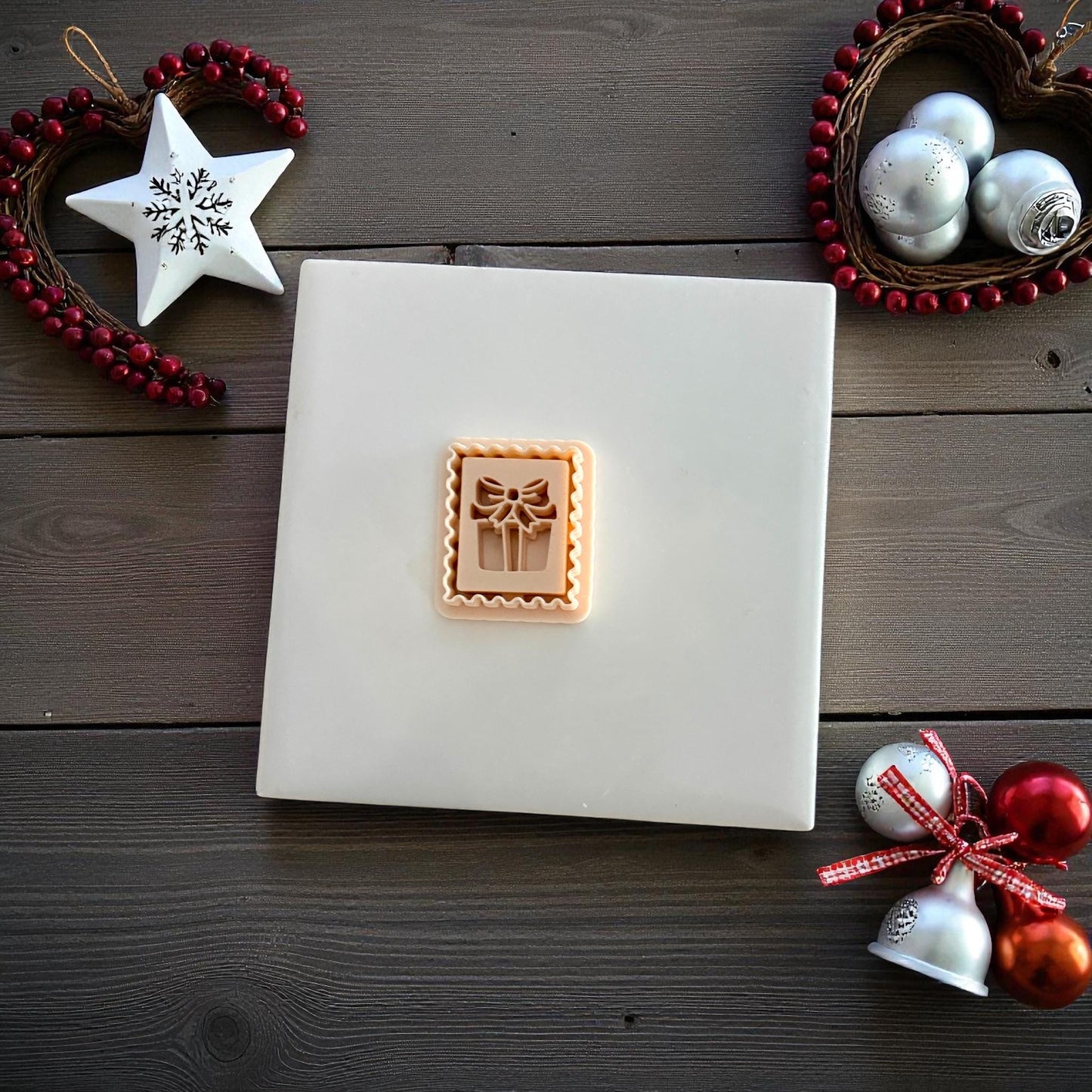 Small gift stamp clay imprint centered on white tile with festive holiday decor