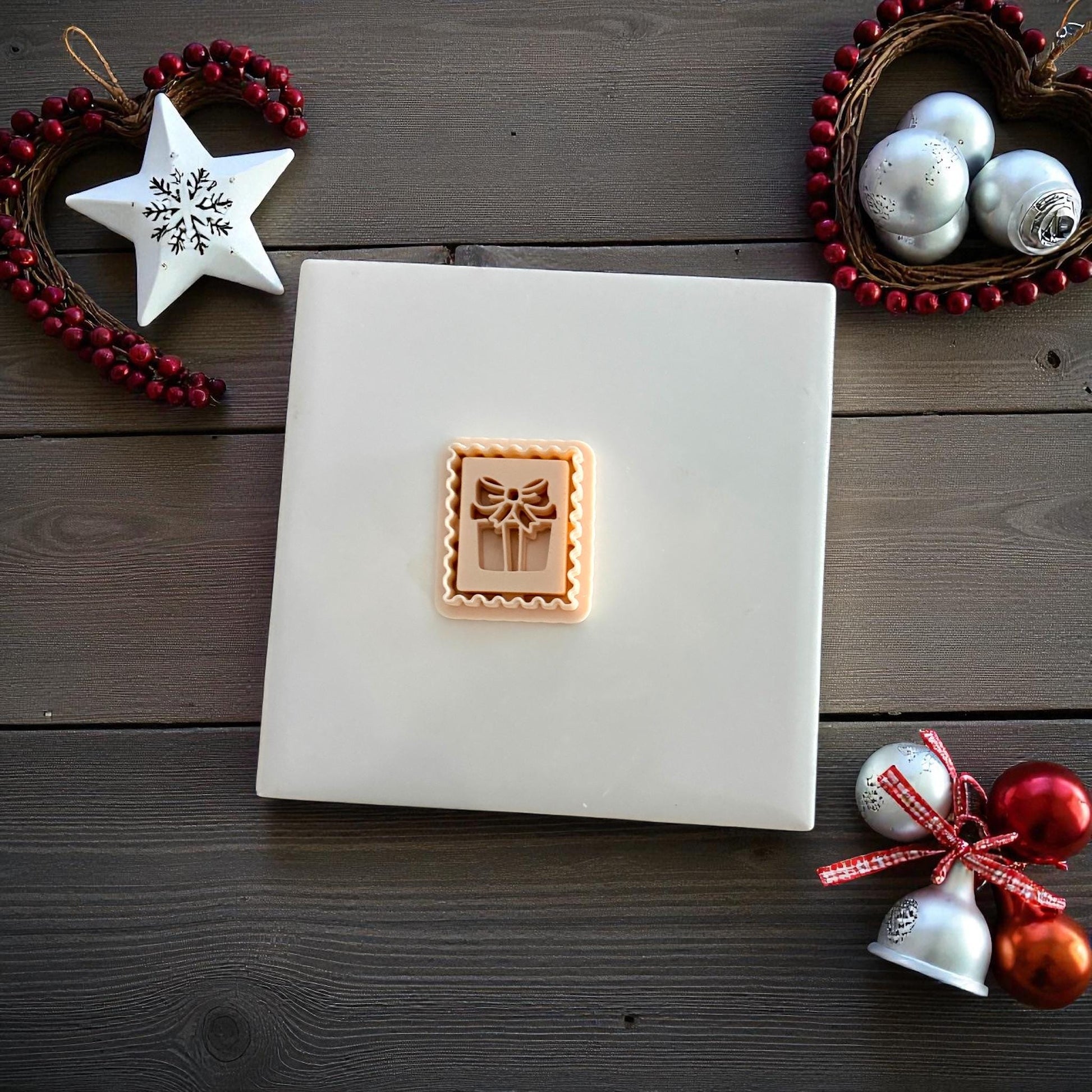 Small gift stamp clay imprint centered on white tile with festive holiday decor