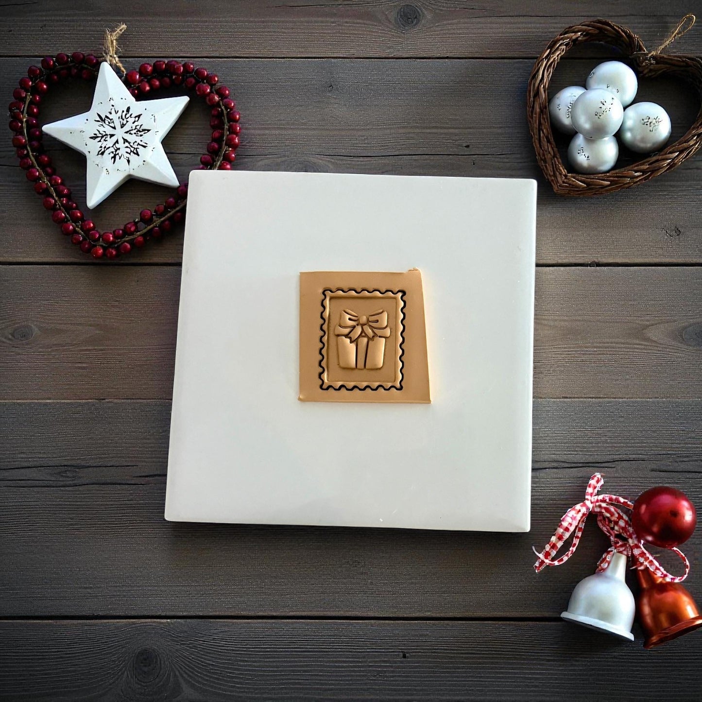 Gift stamp clay imprint pressed into clay sheet on white tile with Christmas decorations