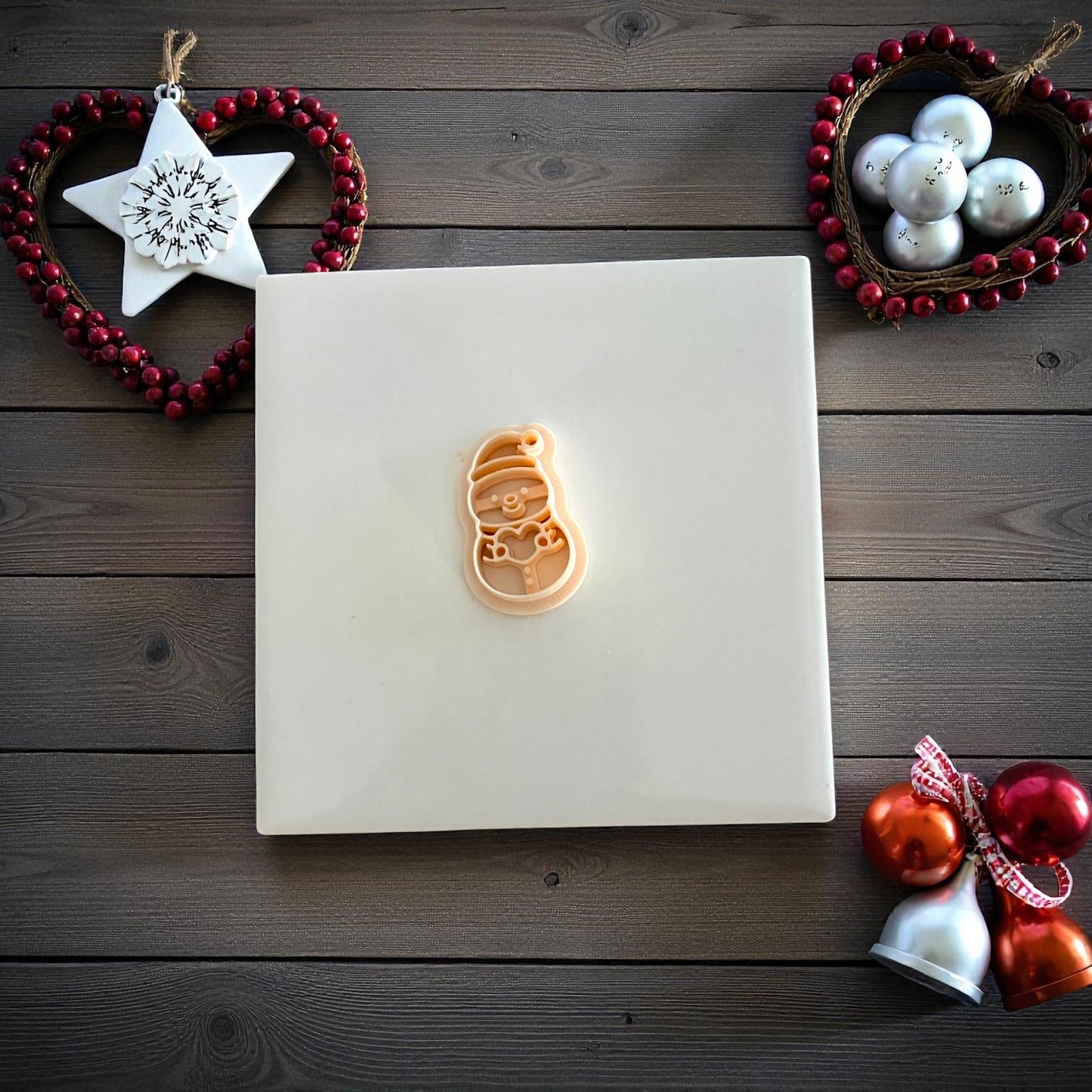 Snowman clay imprint centered on white tile with festive Christmas ornaments