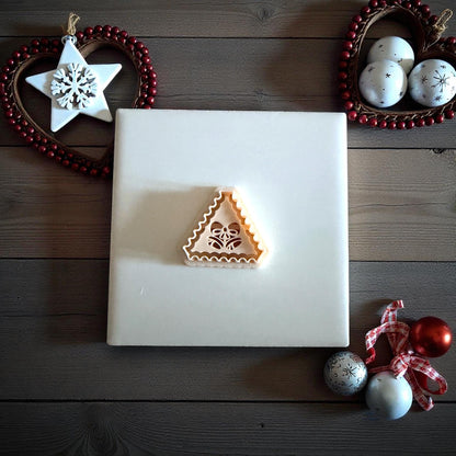 Jingle bell clay imprint centered on white tile with holiday decorations