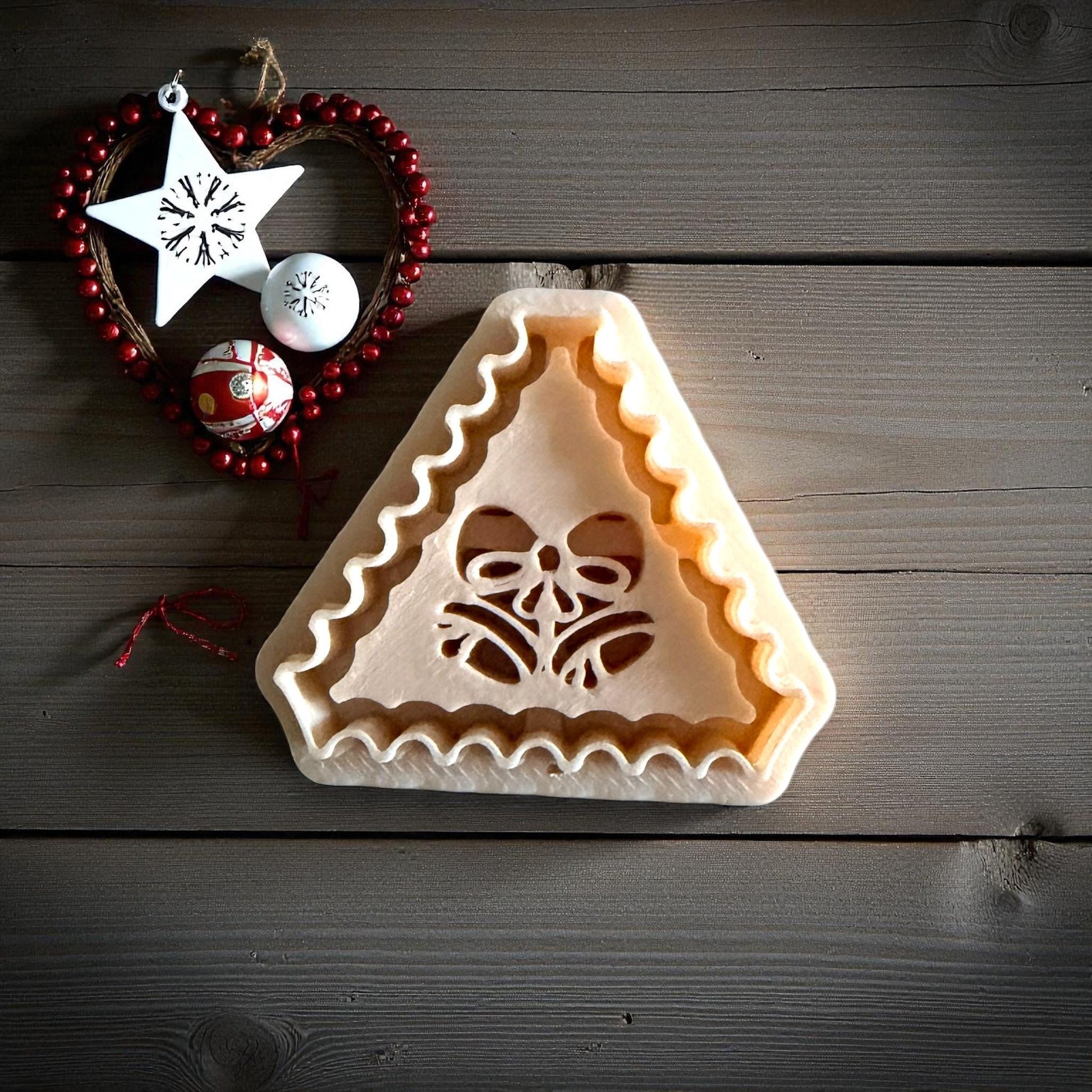 Jingle bell clay imprint pressed into clay sheet on white tile with ornaments nearby