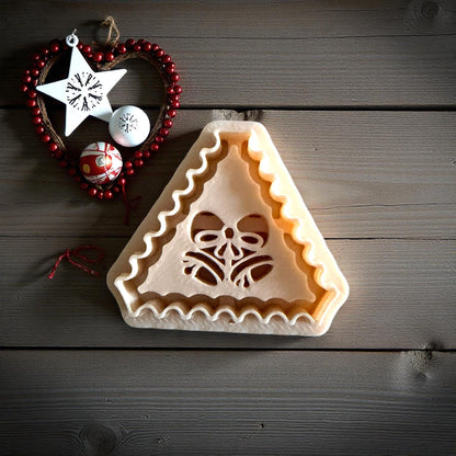 Jingle bell clay imprint pressed into clay sheet on white tile with ornaments nearby