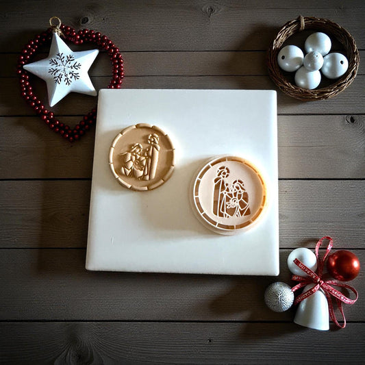 Two round nativity clay imprints side by side on white tile with festive ornaments