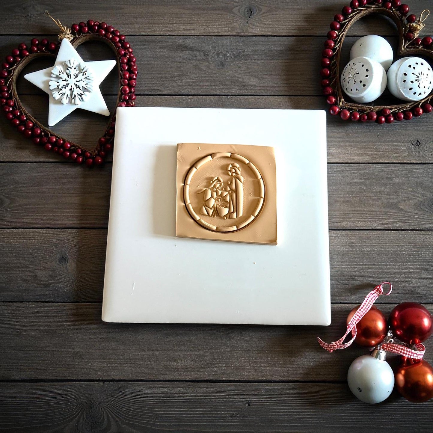 Round nativity clay imprint on wood background with star ornament and red beads