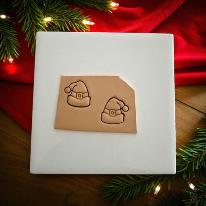 Clay slab with Santa hat impressions surrounded by holiday lights and greenery