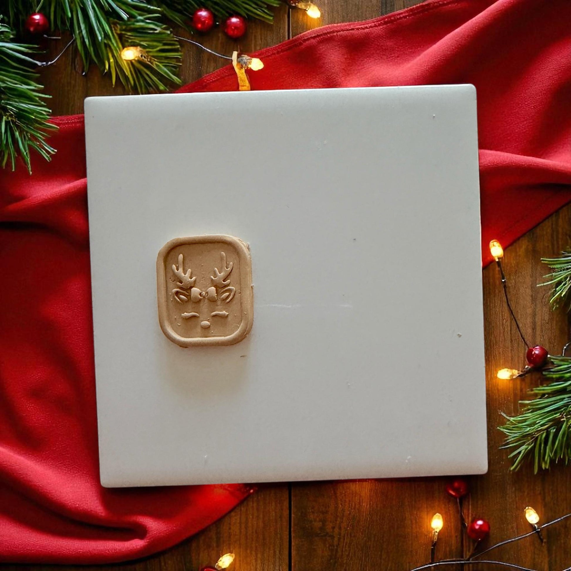 Small reindeer clay design centered on white tile with festive decor