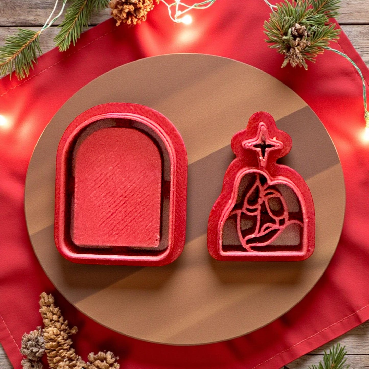 Red Nativity polymer clay cutter set on round board with red fabric and pine decor