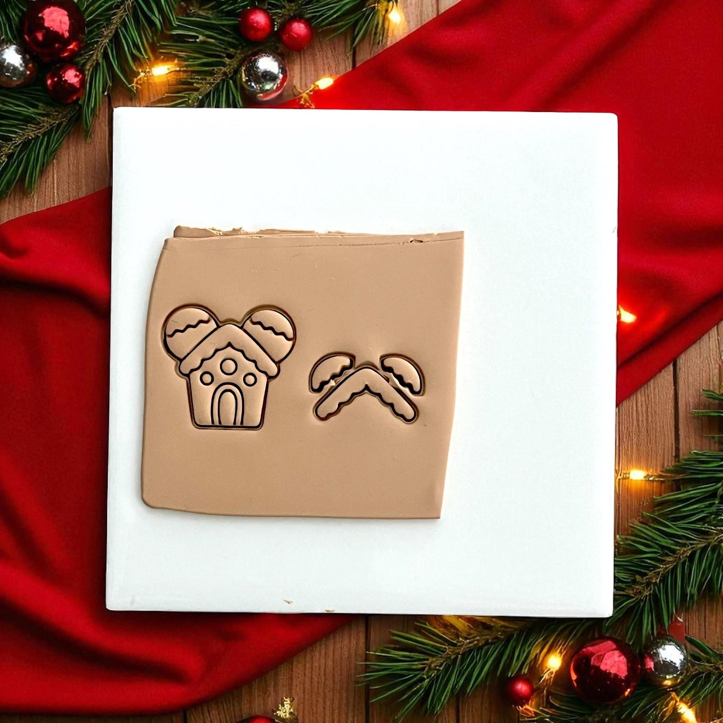 Gingerbread mouse house clay impression on white tile with red fabric and Christmas decor