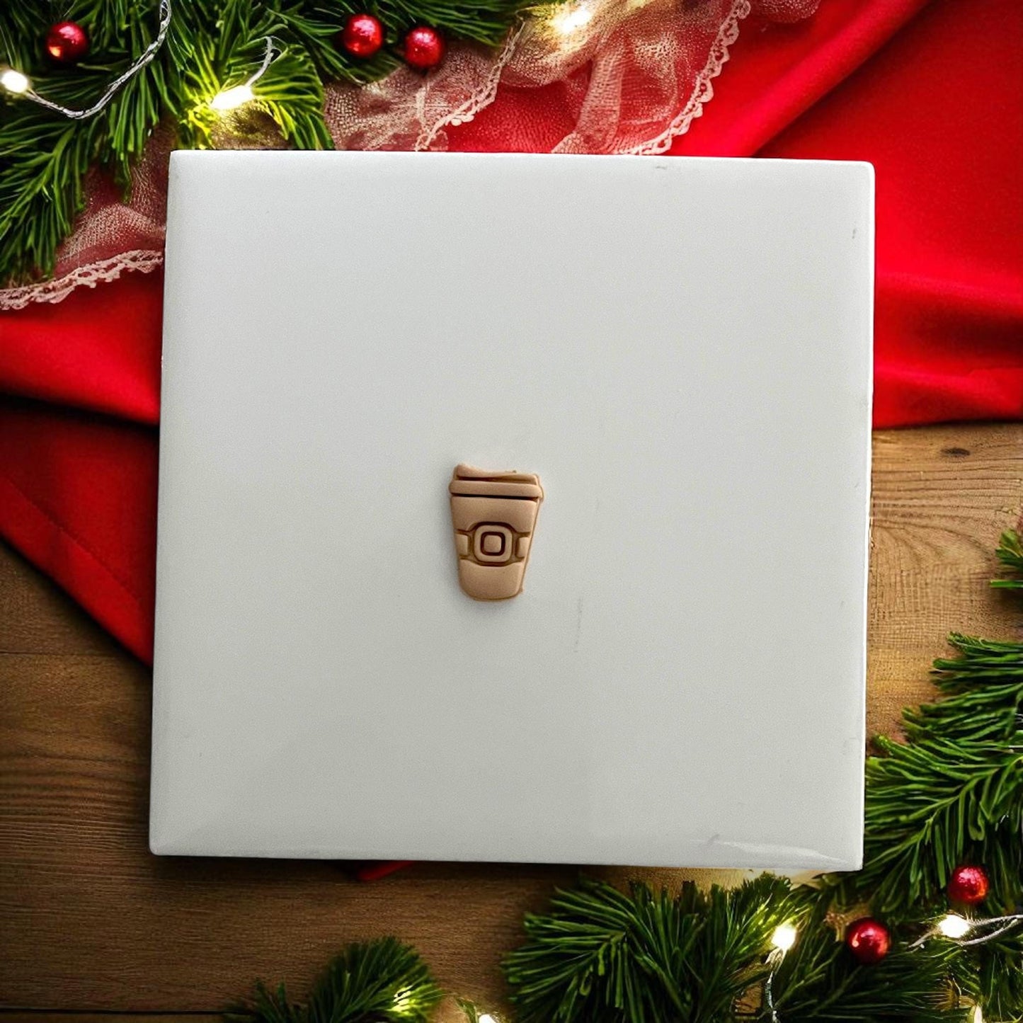 Small Santa coffee cup clay impression on white tile surrounded by festive décor