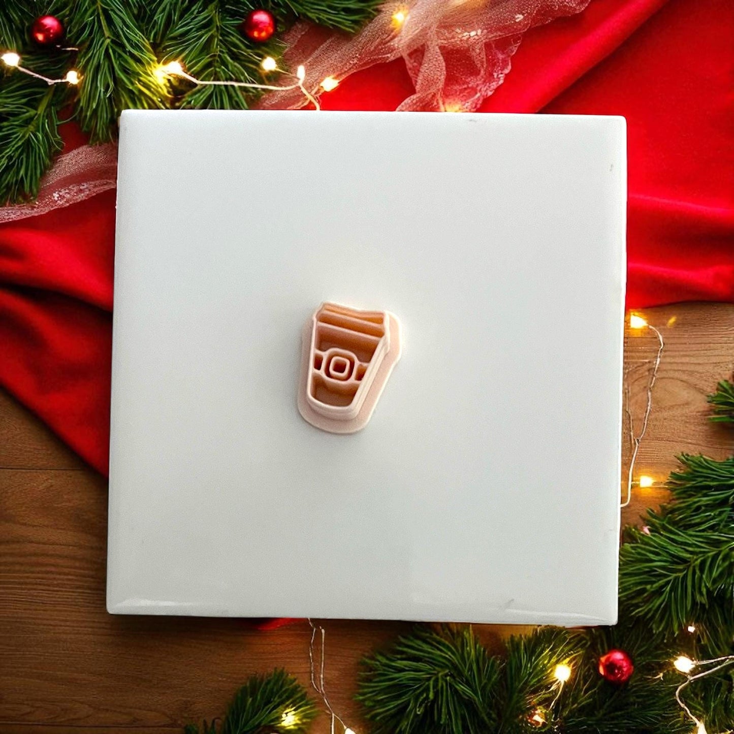 Santa coffee cup cutter on red napkin with pine greenery and Christmas lights